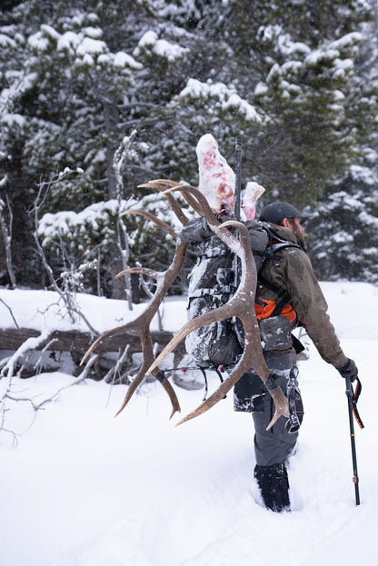 Person carrying elk antlers in a snowy forest