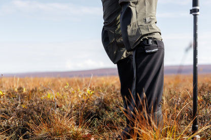 Person wearing outdoor gear with a hiking pole in a field