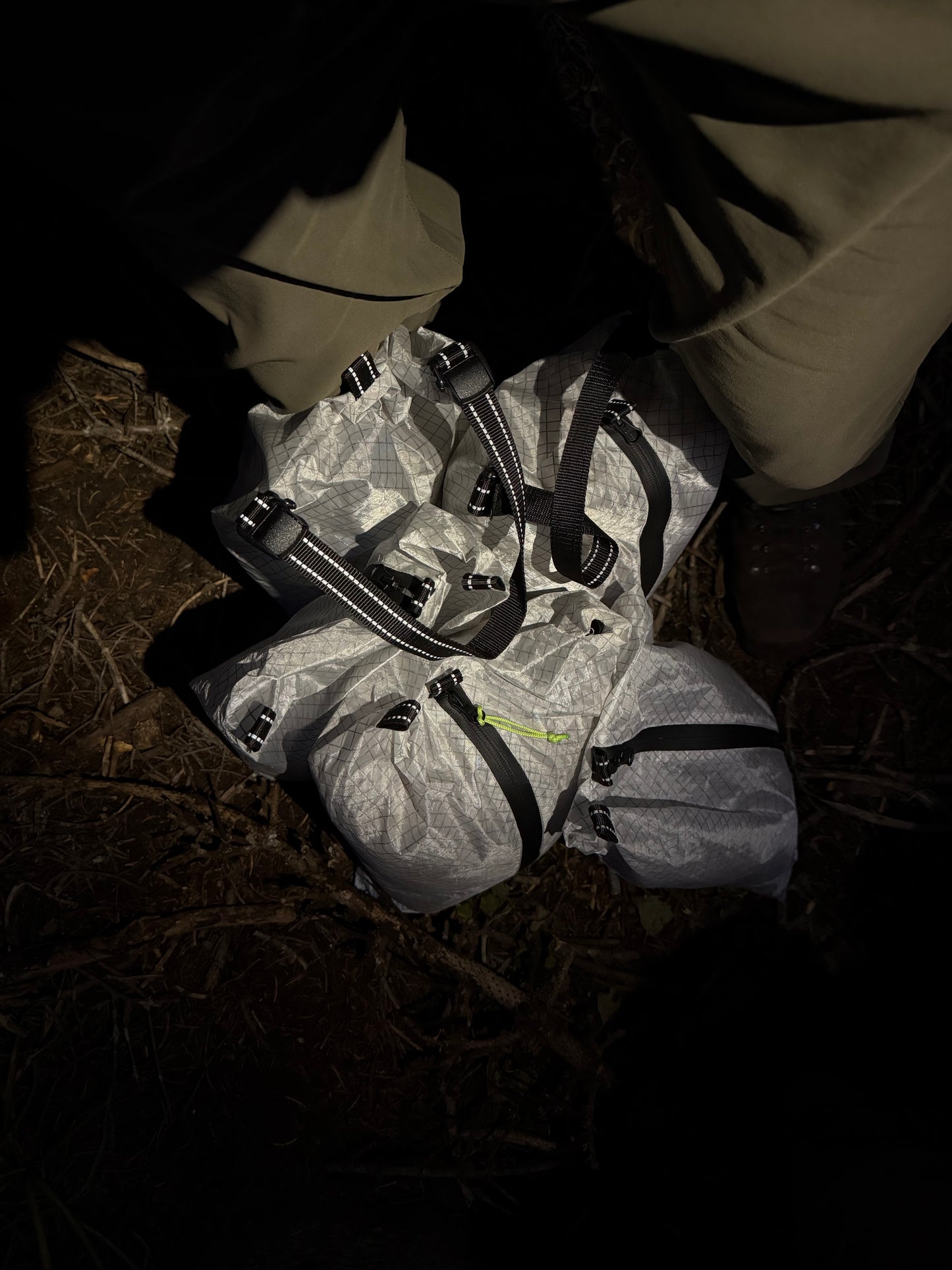 Person lying on the ground next to a backpack in a dark setting