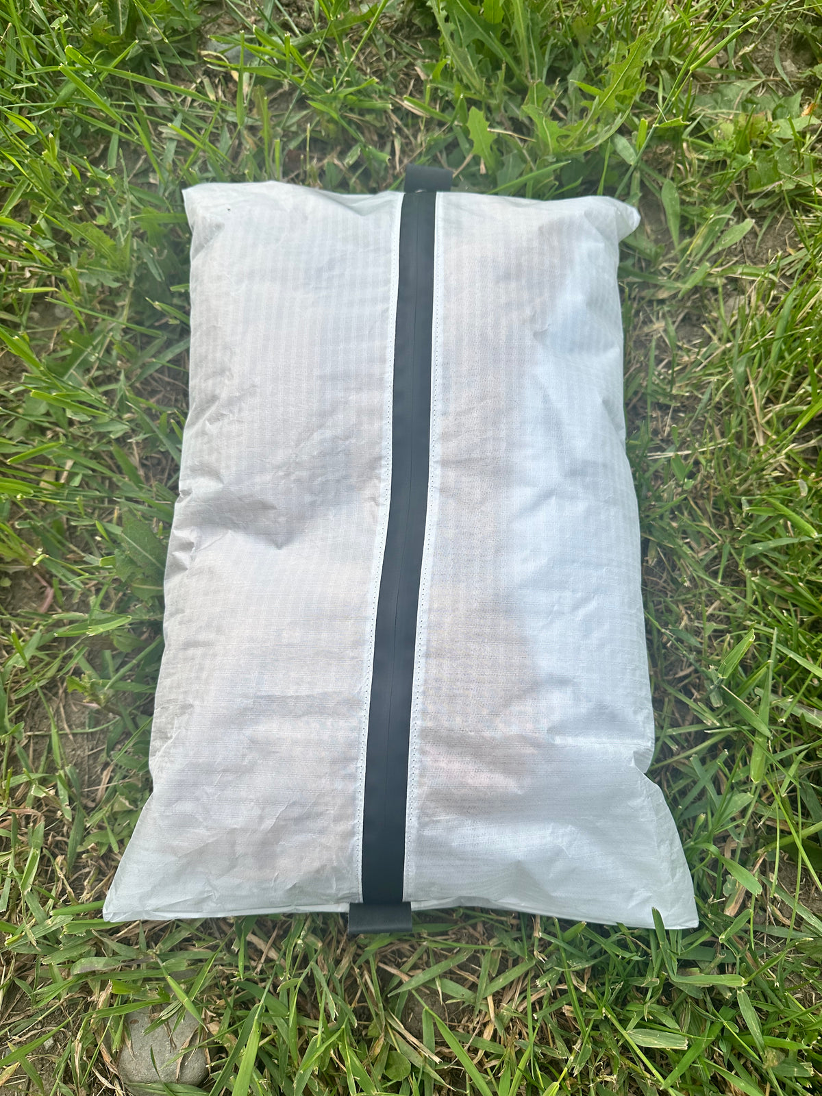 White mesh bag with a black strap on grass